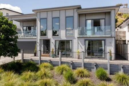 A stylish, single-story home with a modern design, large windows, and a well-kept lawn, listed by The Northern Group, recognized as the Best Real Estate Agent.